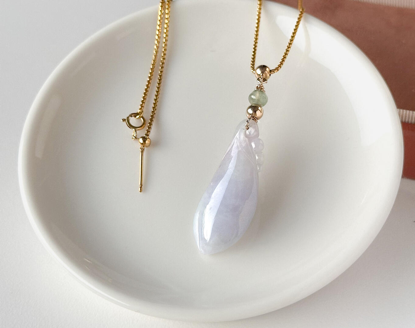 Lavender Tinted Teardrop Shaped Jadeite Pendant on Table